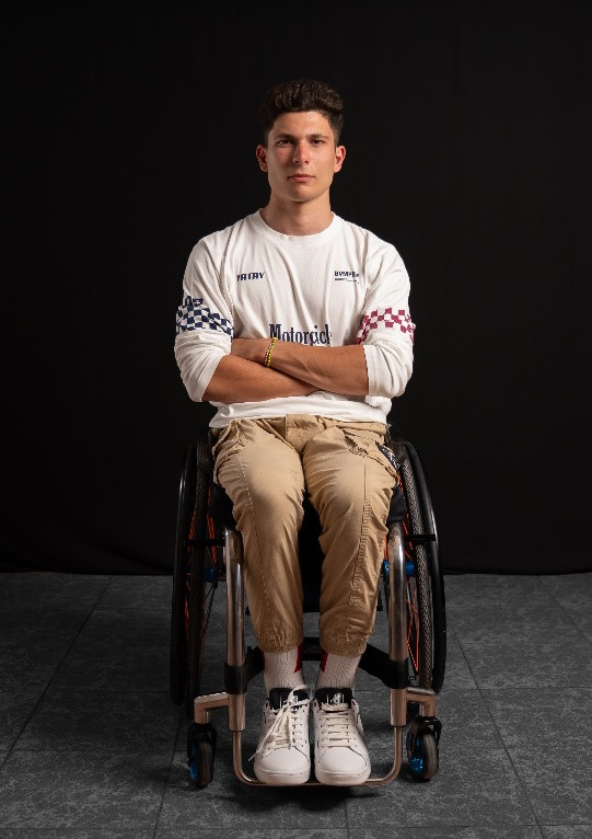 En una silla de ruedas vemos a Carlos Tatay un joven vestido de sport y con los brazos cruzados.