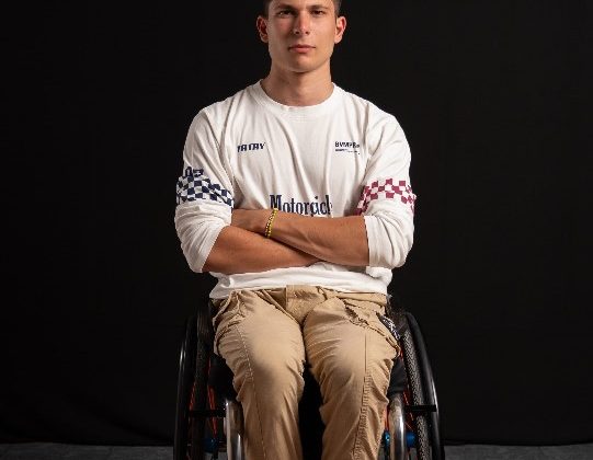 En una silla de ruedas vemos a Carlos Tatay un joven vestido de sport y con los brazos cruzados.